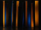 Tall translucent amber and indigo glass panels of varying heights standing against a black background.
